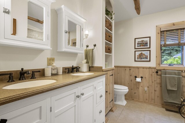 bathroom featuring tile patterned flooring, vanity, toilet, and wooden walls