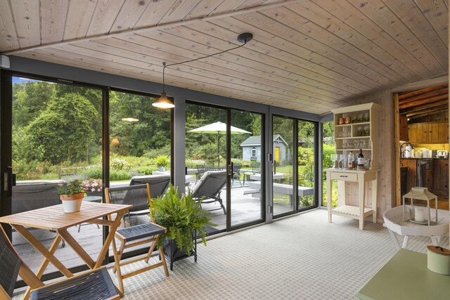 sunroom / solarium with lofted ceiling, wooden ceiling, and a wealth of natural light