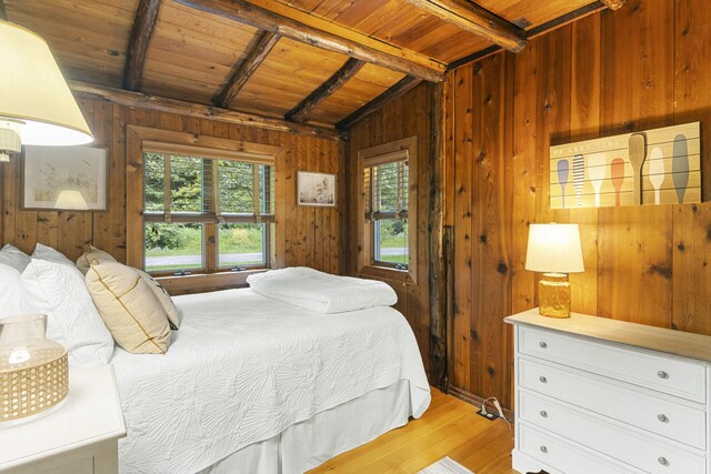 bedroom with wood walls, lofted ceiling with beams, light hardwood / wood-style floors, and wood ceiling