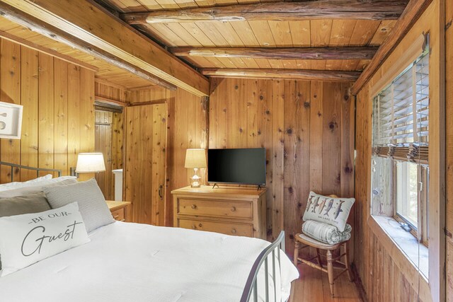 bedroom featuring beamed ceiling, hardwood / wood-style floors, wooden walls, and wood ceiling