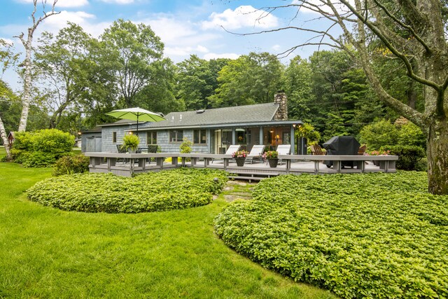 back of house featuring a lawn and a wooden deck