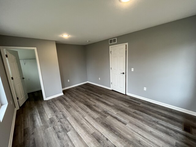 unfurnished bedroom featuring a spacious closet, a closet, and dark hardwood / wood-style floors