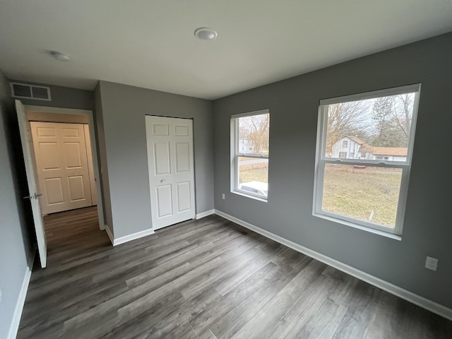 unfurnished bedroom featuring hardwood / wood-style floors, a closet, and multiple windows