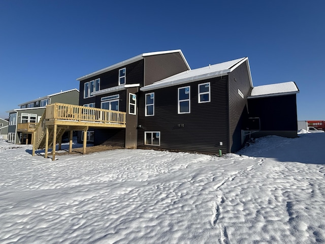 snow covered back of property featuring a deck