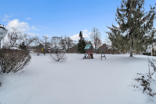 snowy yard featuring a playground