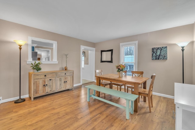 dining space with light wood-style flooring and baseboards