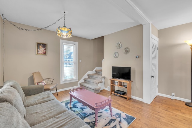 living room featuring stairs, light wood finished floors, and baseboards