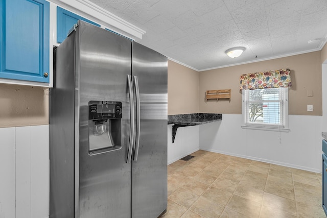 kitchen with blue cabinets, stainless steel fridge, visible vents, and ornamental molding