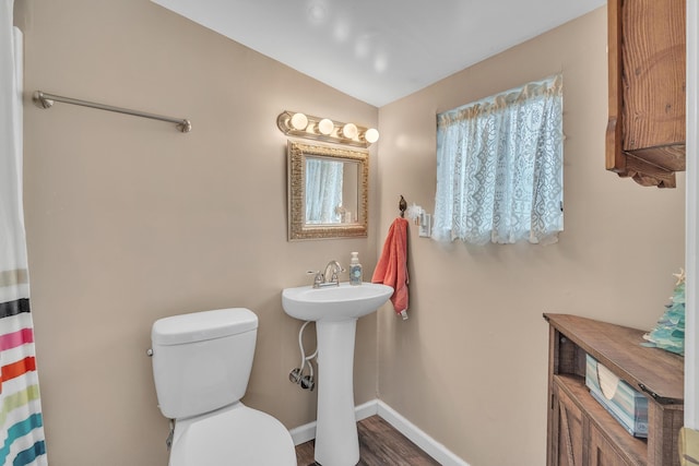 bathroom featuring baseboards, toilet, wood finished floors, vaulted ceiling, and a sink