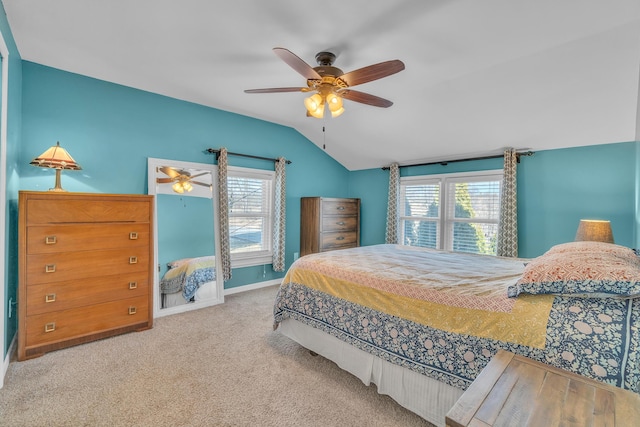 carpeted bedroom featuring vaulted ceiling, multiple windows, a ceiling fan, and baseboards