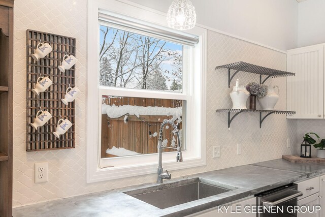 interior details featuring decorative light fixtures, dishwasher, white cabinetry, and sink