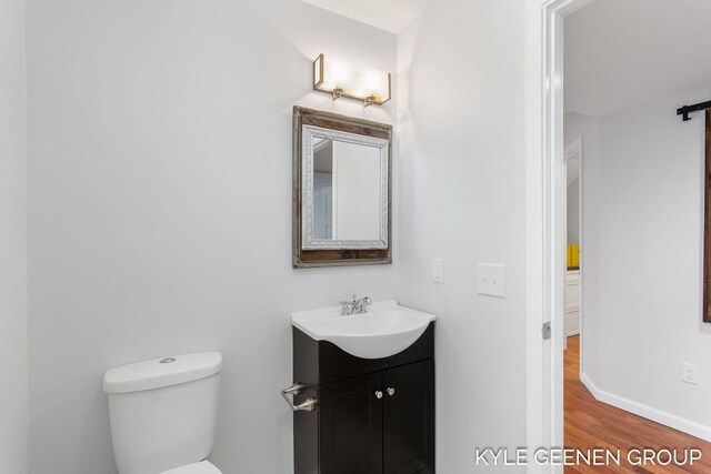 bathroom featuring wood-type flooring, vanity, and toilet