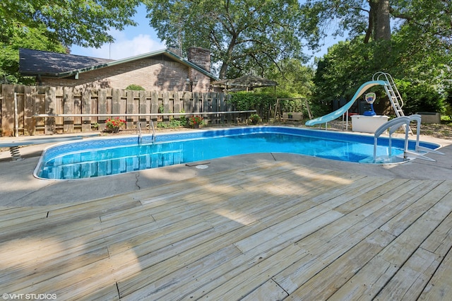 view of swimming pool with a wooden deck and a water slide