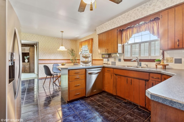 884 Oakridge Dr, Saint Joseph, MI 49085 - kitchen featuring a sink, stainless steel appliances, brown cabinetry, a peninsula, and wallpapered walls