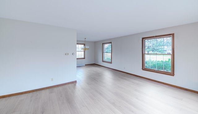 884 Oakridge Dr, Saint Joseph, MI 49085 - spare room with a notable chandelier, baseboards, and light wood-style floors