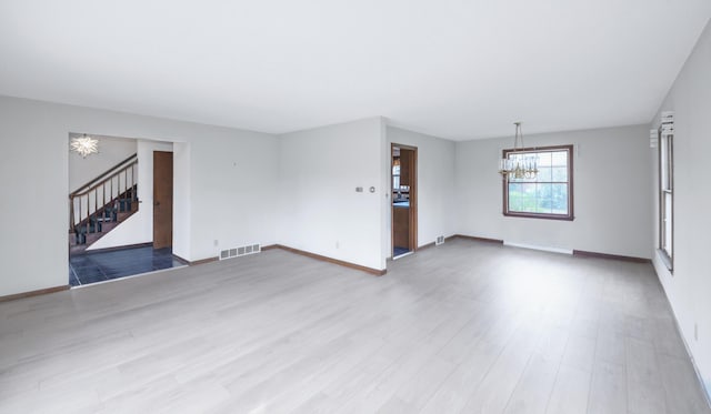 884 Oakridge Dr, Saint Joseph, MI 49085 - unfurnished living room featuring light wood-style flooring, stairway, visible vents, baseboards, and an inviting chandelier