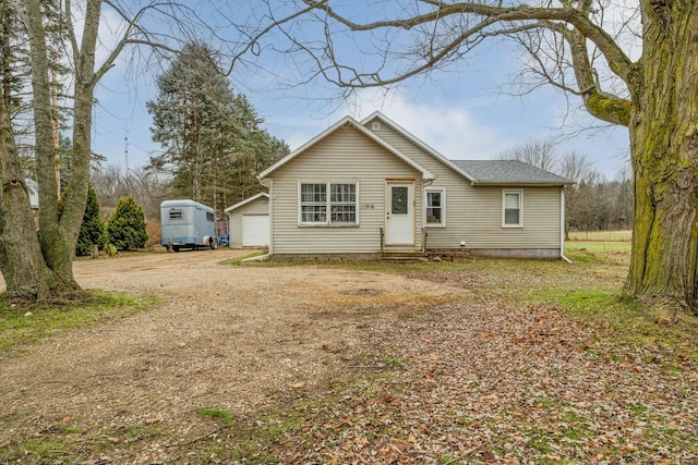 rear view of property featuring a garage and an outbuilding