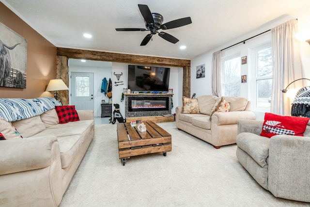 carpeted living room with ceiling fan and a stone fireplace