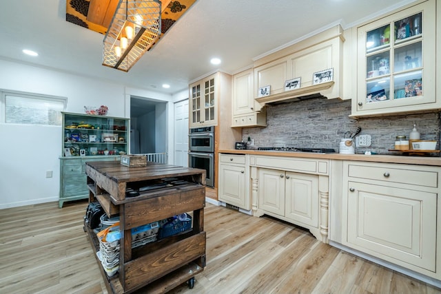 kitchen with cream cabinetry, tasteful backsplash, gas cooktop, and light hardwood / wood-style flooring