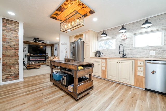 kitchen featuring sink, ceiling fan, light wood-type flooring, appliances with stainless steel finishes, and brick wall