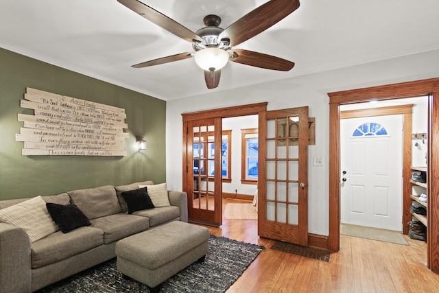 living room featuring french doors, light wood-type flooring, ceiling fan, and crown molding