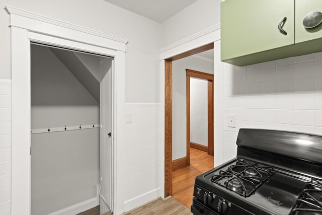 kitchen with light hardwood / wood-style floors, black gas range oven, and green cabinetry