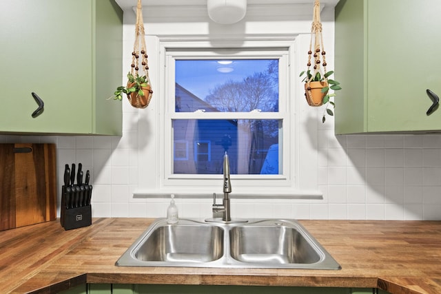 kitchen with backsplash, green cabinets, butcher block counters, and sink