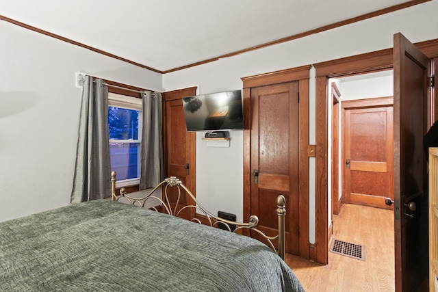 bedroom with light wood-type flooring and ornamental molding