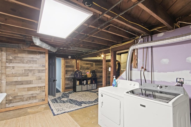 washroom with washing machine and clothes dryer and wooden walls