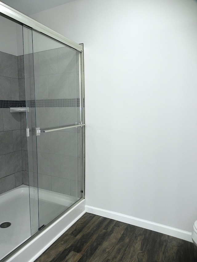 bathroom featuring hardwood / wood-style floors, toilet, and a shower with shower door