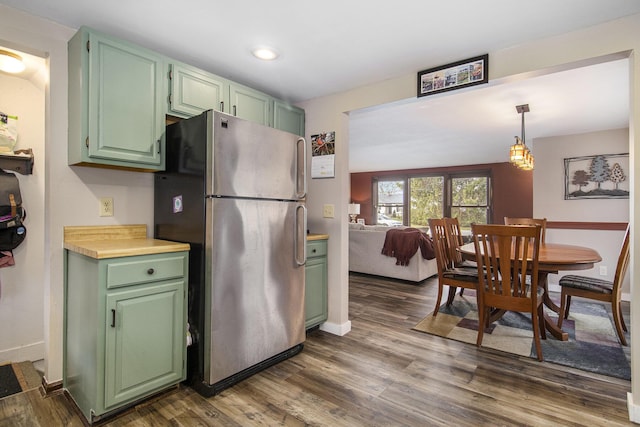 kitchen with stainless steel refrigerator, hanging light fixtures, green cabinets, dark hardwood / wood-style flooring, and vaulted ceiling