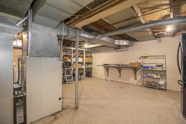 basement featuring carpet flooring, refrigerator, and heating unit