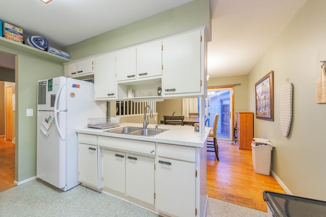 kitchen with white cabinets, light wood-type flooring, white fridge, and sink