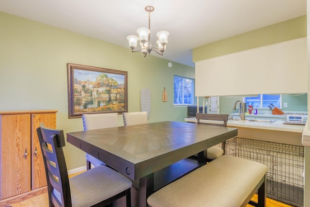 dining room with sink, a chandelier, and light wood-type flooring