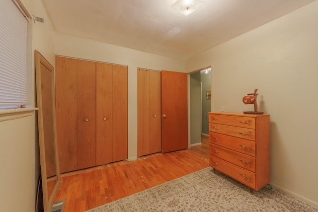 bedroom featuring light hardwood / wood-style floors and multiple closets