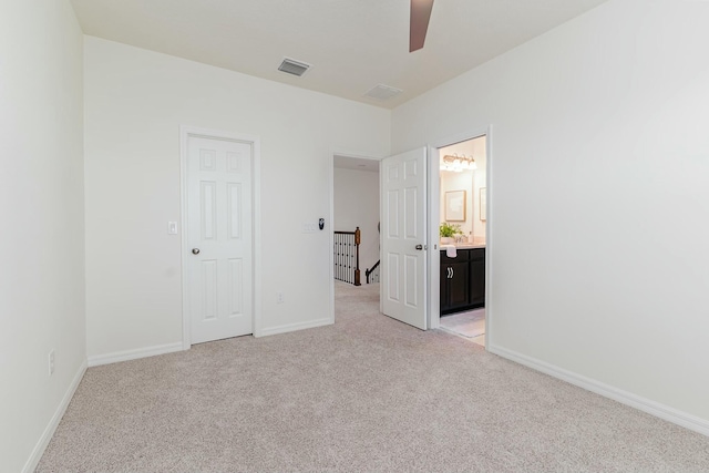 unfurnished bedroom with ensuite bath, ceiling fan, a closet, and light colored carpet