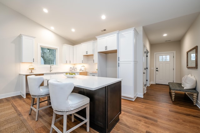 kitchen featuring tasteful backsplash, white cabinetry, a kitchen island, and hardwood / wood-style flooring