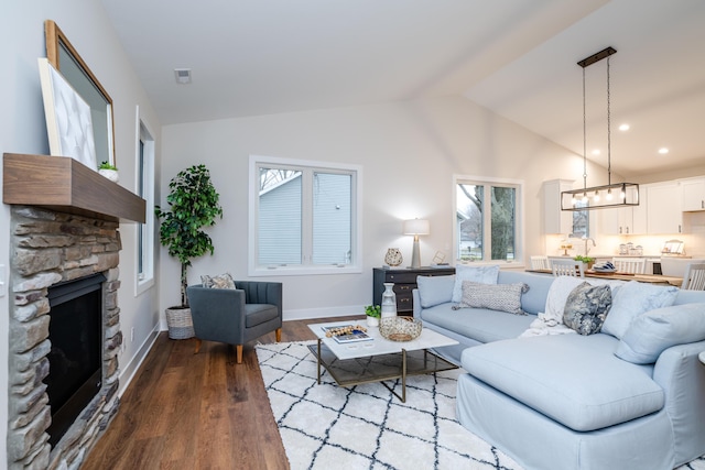 living room featuring a stone fireplace, hardwood / wood-style floors, and vaulted ceiling