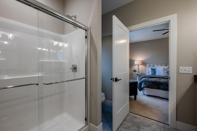 bathroom with ceiling fan, a shower with door, and toilet