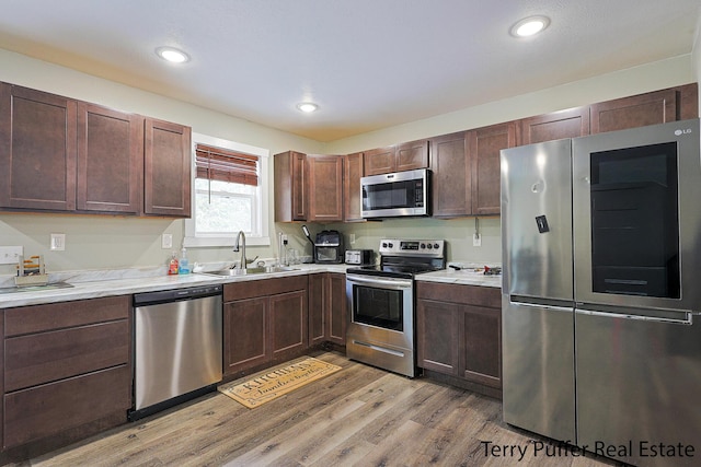 kitchen featuring dark brown cabinets, light hardwood / wood-style floors, sink, and stainless steel appliances