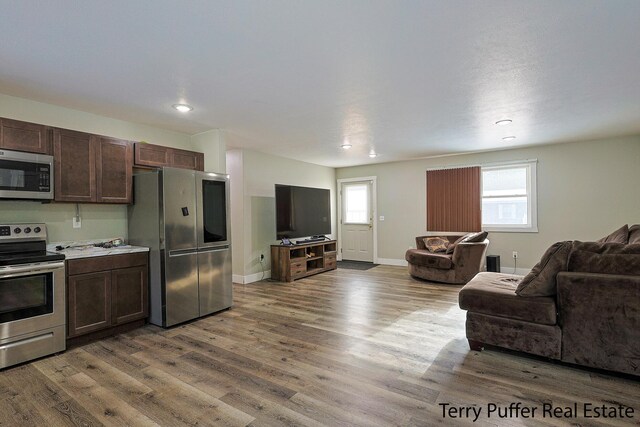 kitchen featuring dark brown cabinetry, hardwood / wood-style flooring, and appliances with stainless steel finishes