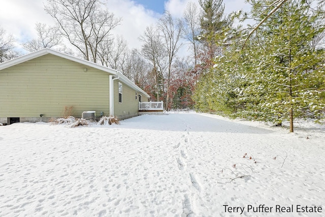 snowy yard with a deck and cooling unit