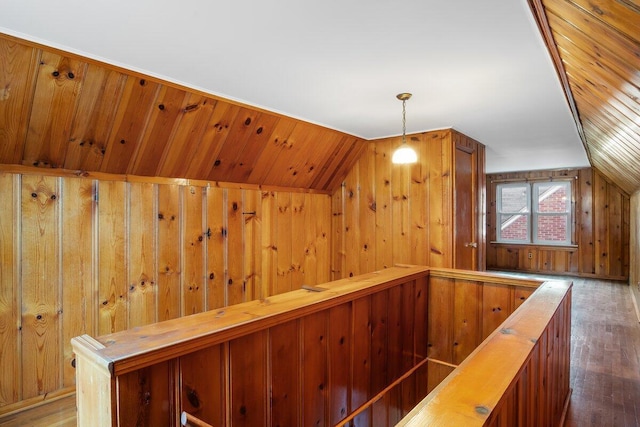 hallway featuring dark hardwood / wood-style flooring, lofted ceiling, and wood walls