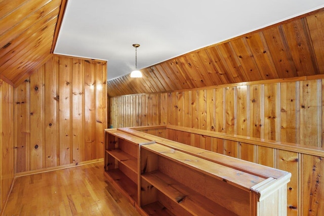 additional living space featuring light wood-type flooring, lofted ceiling, and wooden walls