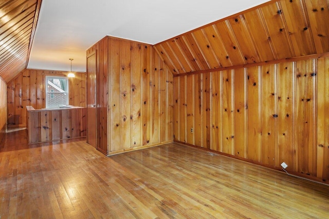 bonus room featuring wood walls, light hardwood / wood-style flooring, and lofted ceiling