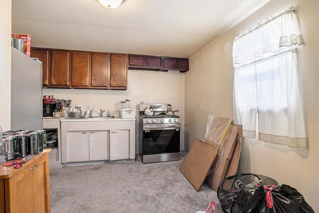 kitchen with sink, light colored carpet, and stainless steel range oven