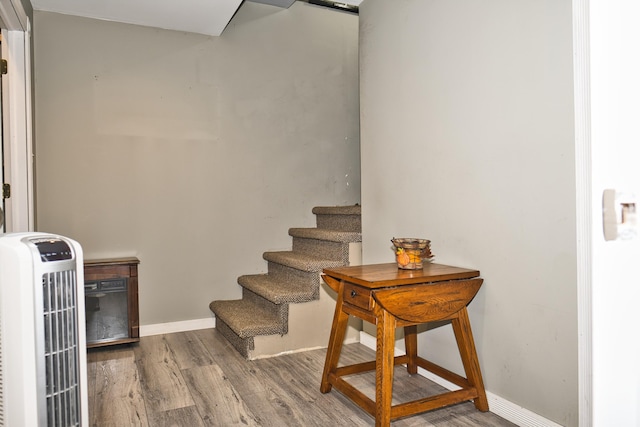 staircase with hardwood / wood-style floors and heating unit