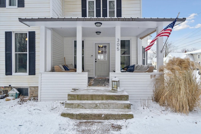 snow covered property entrance featuring a porch