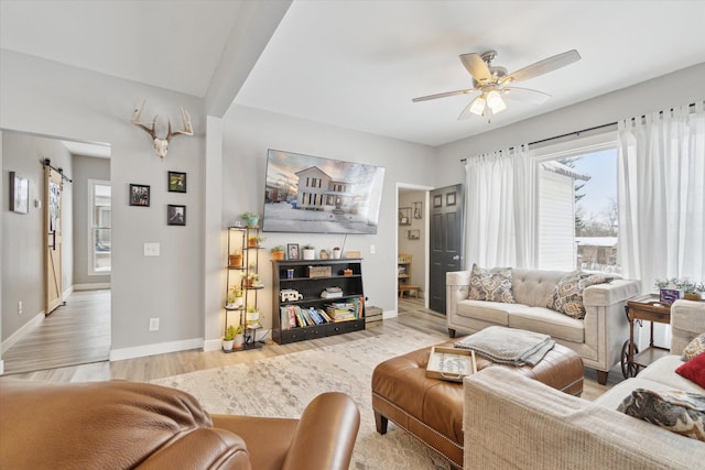 living room featuring a barn door, light hardwood / wood-style flooring, and ceiling fan