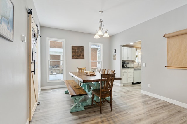 dining room featuring sink, light hardwood / wood-style flooring, and an inviting chandelier